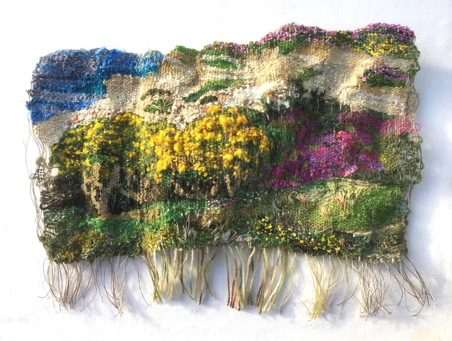 Hand woven 3D tapestry landscape in shades of green, pink, yellow and blue