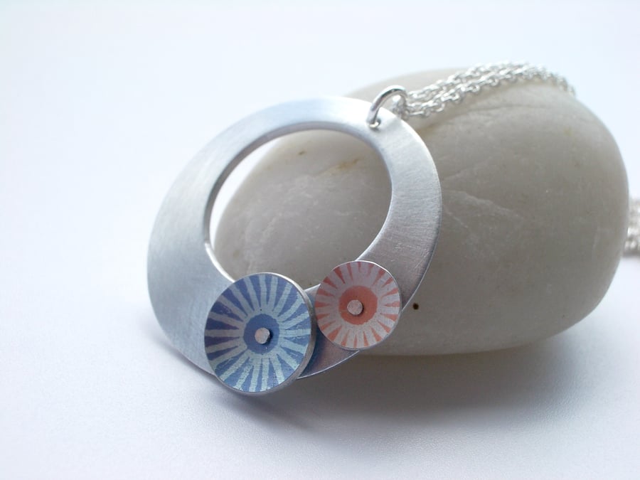 Silver coloured aluminium disc pendant necklace with blue and orange circles