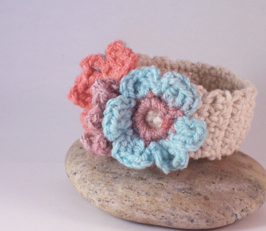Crochet cuff with three floral blooms in aqua, peach and mauve 