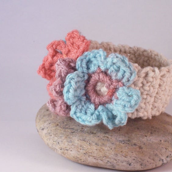 Crochet cuff with three floral blooms in aqua, peach and mauve 