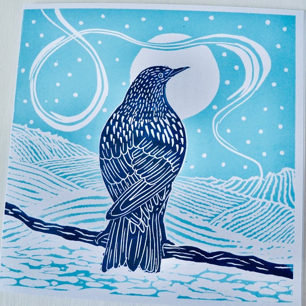 A freshly printed linocut card featuring a starling gazing at the moon