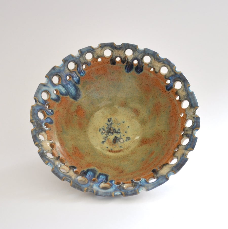 Decorative ceramic bowl with pierced rim in shades of chalk, blue, orange, green