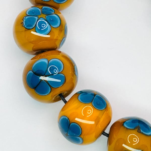 Handmade teal and mustard daisy patterned lamp work glass beads