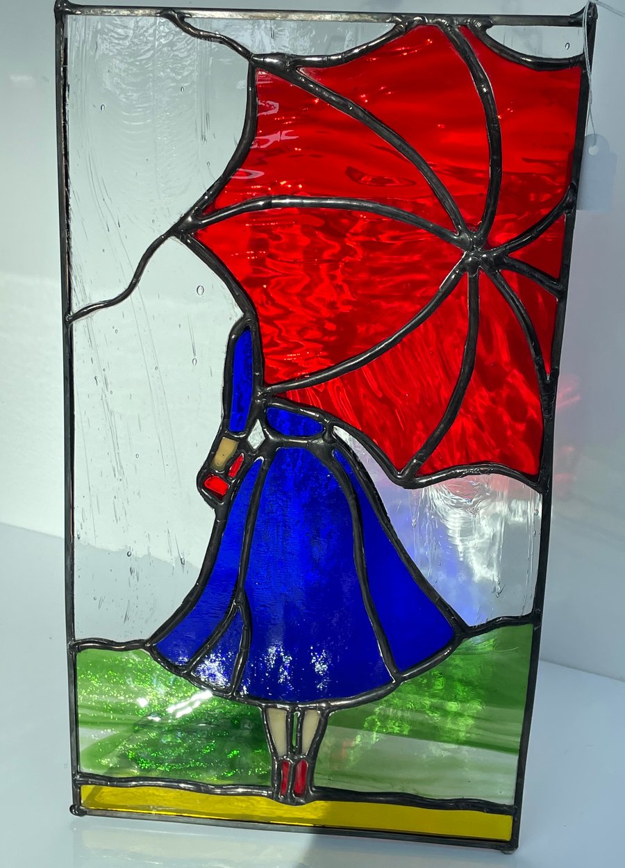 Stained glass panel of lady with umbrella. Zinc framed 