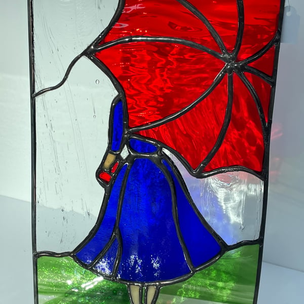 Stained glass panel of lady with umbrella. Zinc framed 