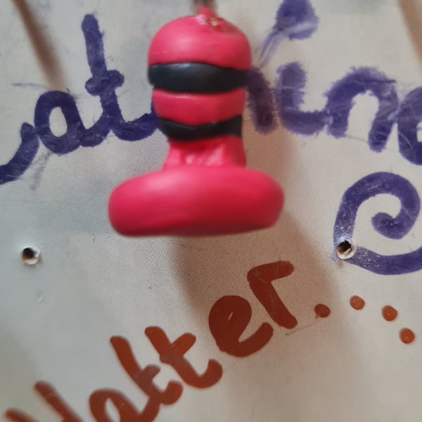 Black and red polymer-clay hat charm.