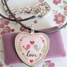 Necklace heart shaped features two birds facing each other with Love 