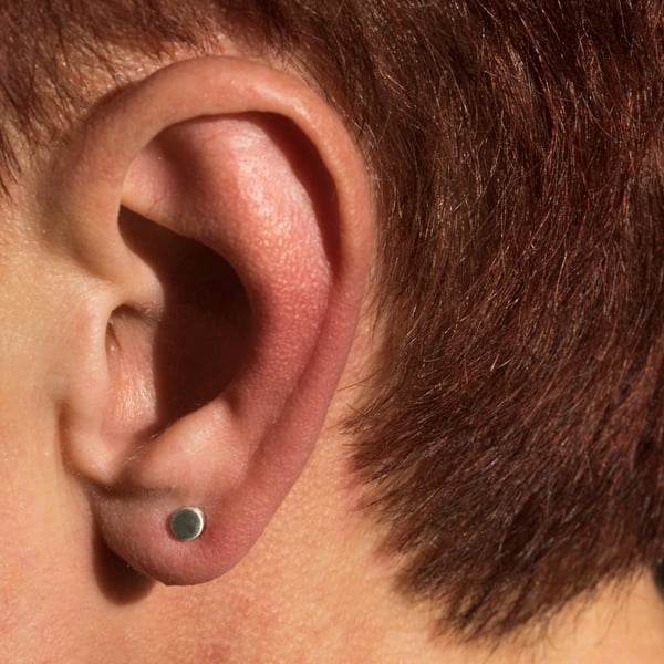 Silver cylindrical ear studs with a brush matte texture