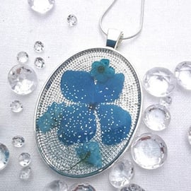 Wide Oval Resin Pendant With Blue Flower Petals