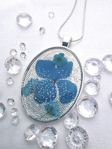Wide Oval Resin Pendant With Blue Flower Petals