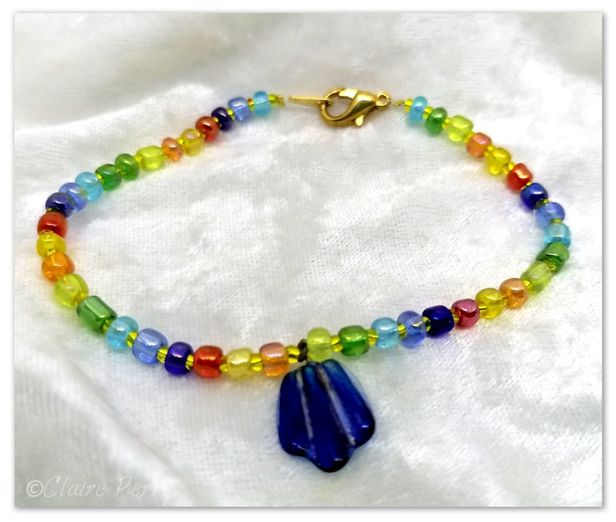 Seed bead bracelet with rainbow coloured glass beads with a blue glass charm.