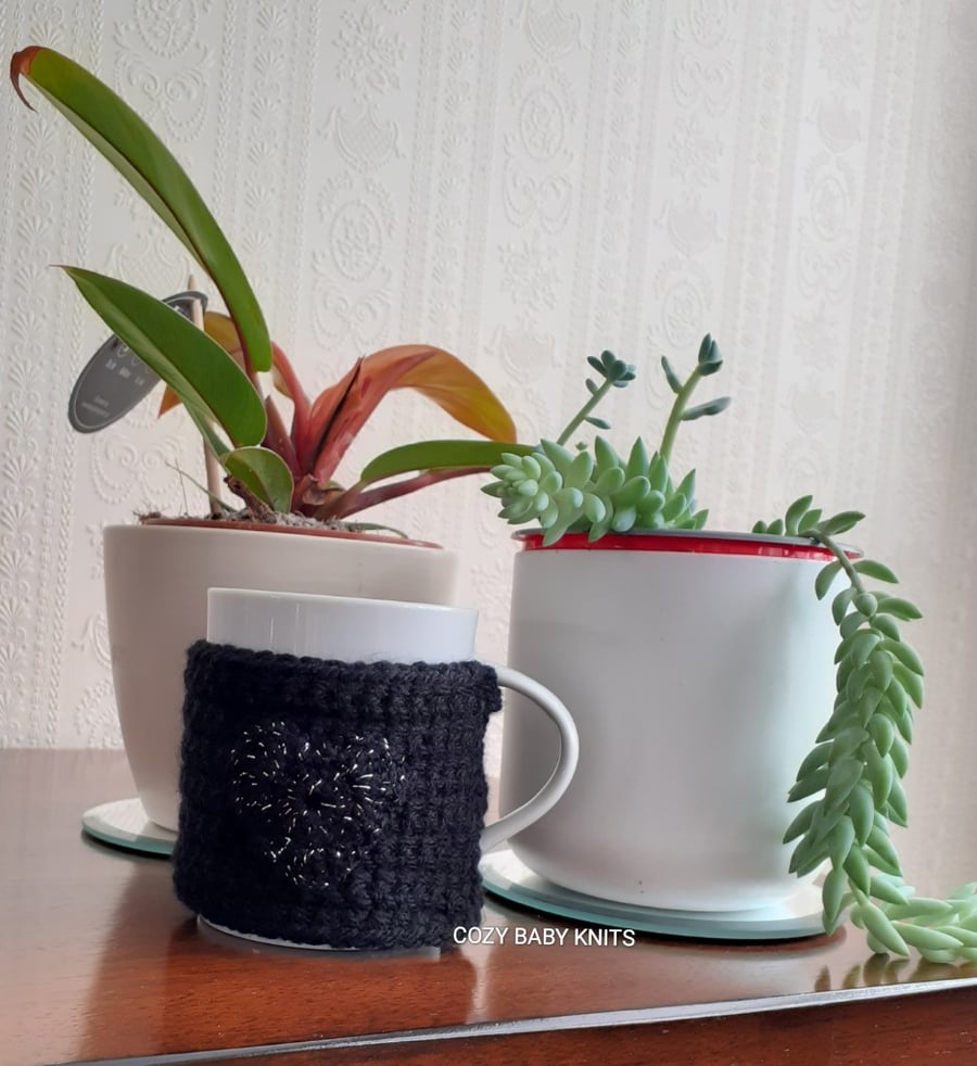 BLACK CROCHET MUG COZY WITH A GLITTERY HEART ON EITHER SIDE 