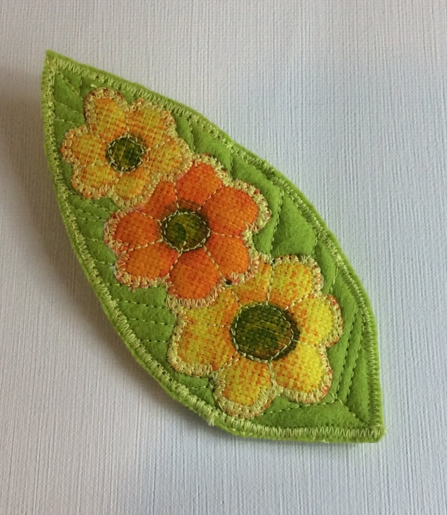 Large felt brooch, flowers on green leaf.
