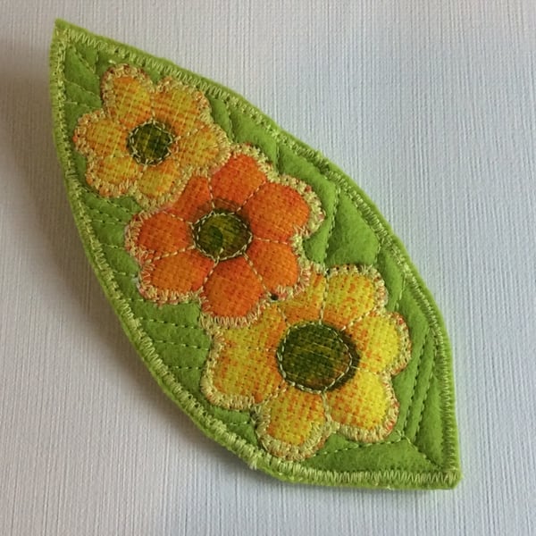 Large felt brooch, flowers on green leaf.