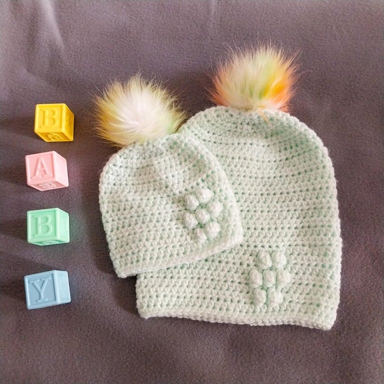 Matching ladies and baby green crocheted hats with detachable faux fur pompoms 