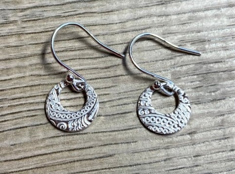 Circular silver earrings with cut out circle and pretty, embossed pattern