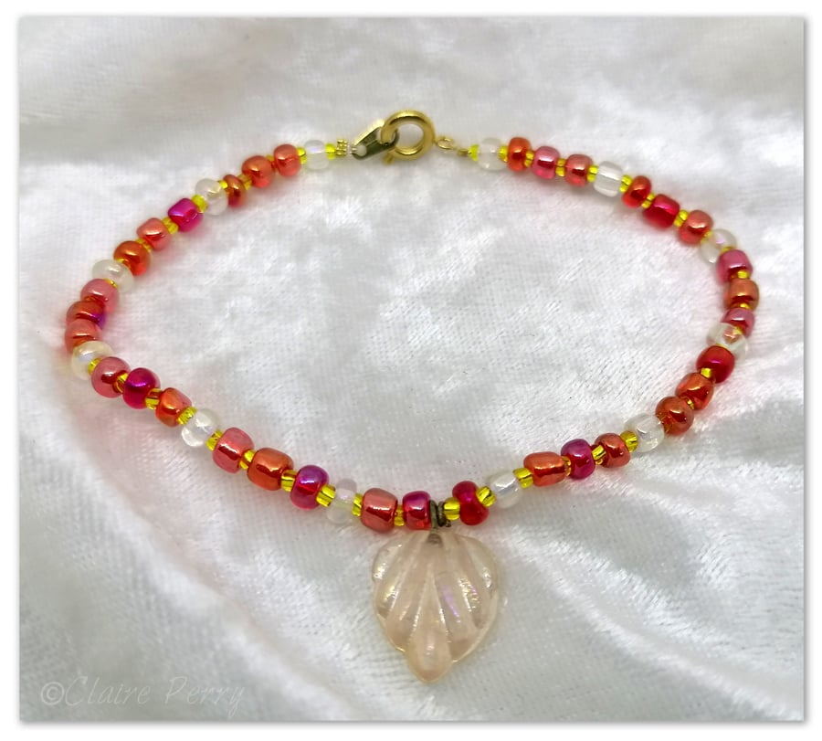 Seed bead bracelet with red coloured glass beads with a pale pink glass charm.