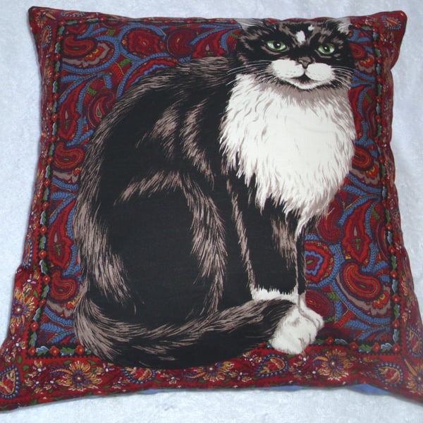 Tapestry cat cushion with a black and white cat sitting waiting patiently