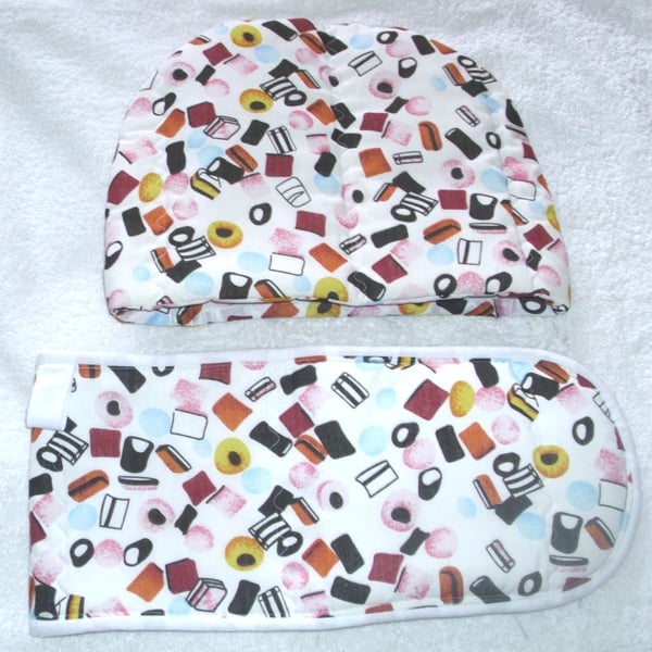 Liquorice Allsorts tossed on white tea cosy and ovengloves