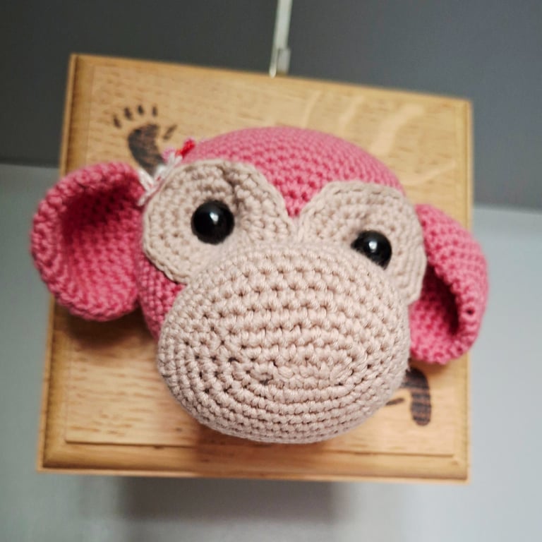 Crocheted monkey trophy head on wooden board
