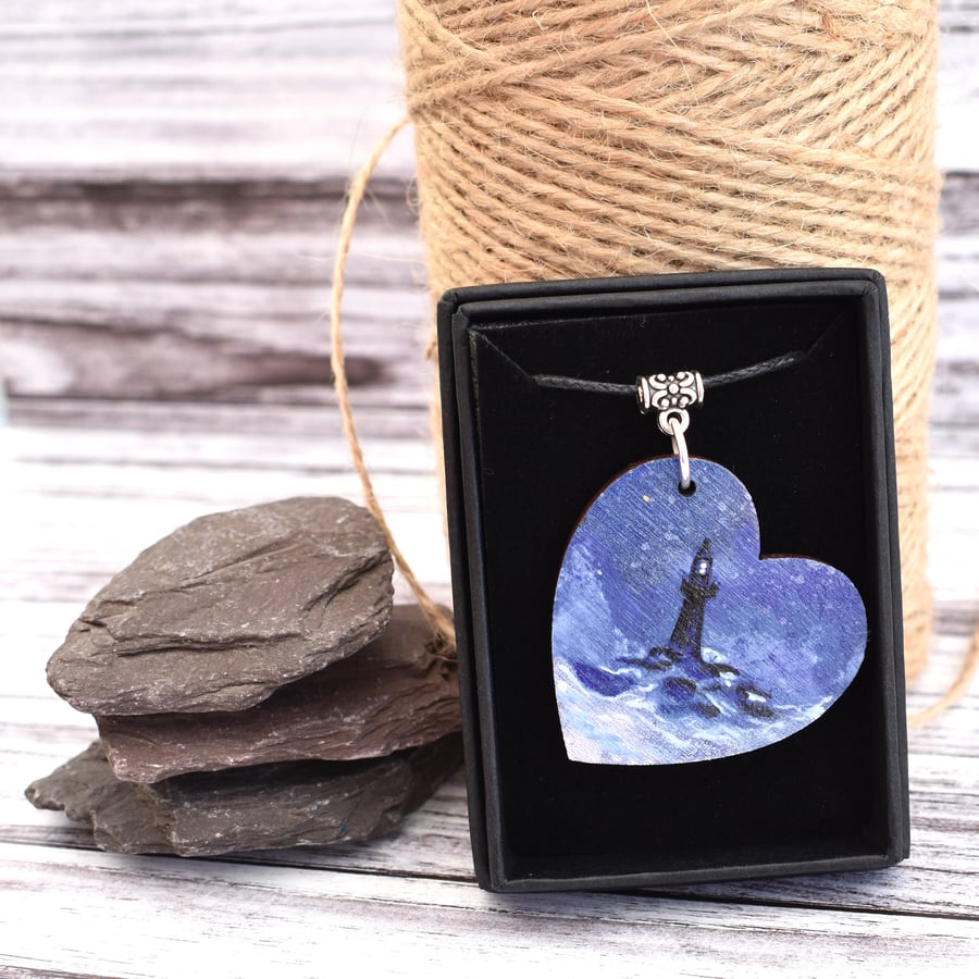 Beacon in the storm. Wooden heart pendant with a lighthouse in stormy seas.
