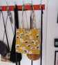 Tote bag made from mustard yellow fabric with flower design.
