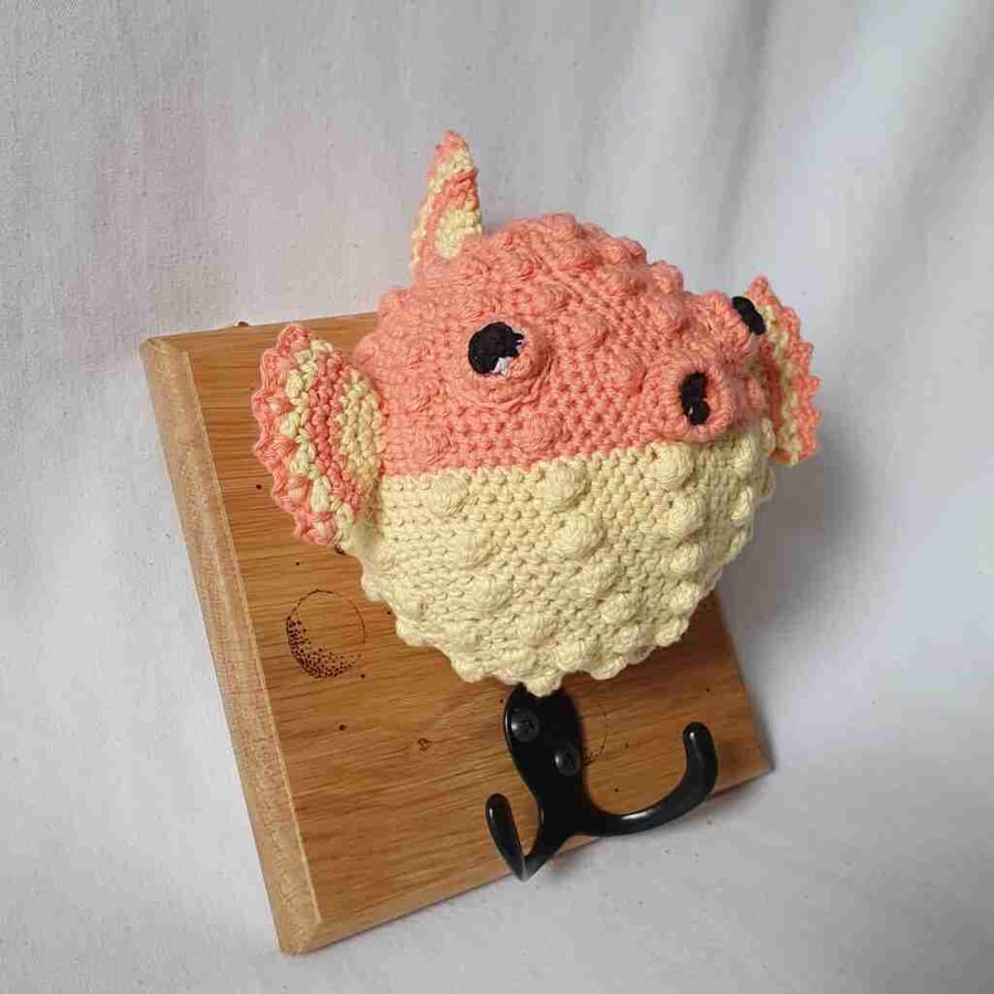 Crocheted puffer fish head on wooden board with hooks