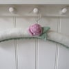 Hand knitted padded coat hanger with a ranunculus flower