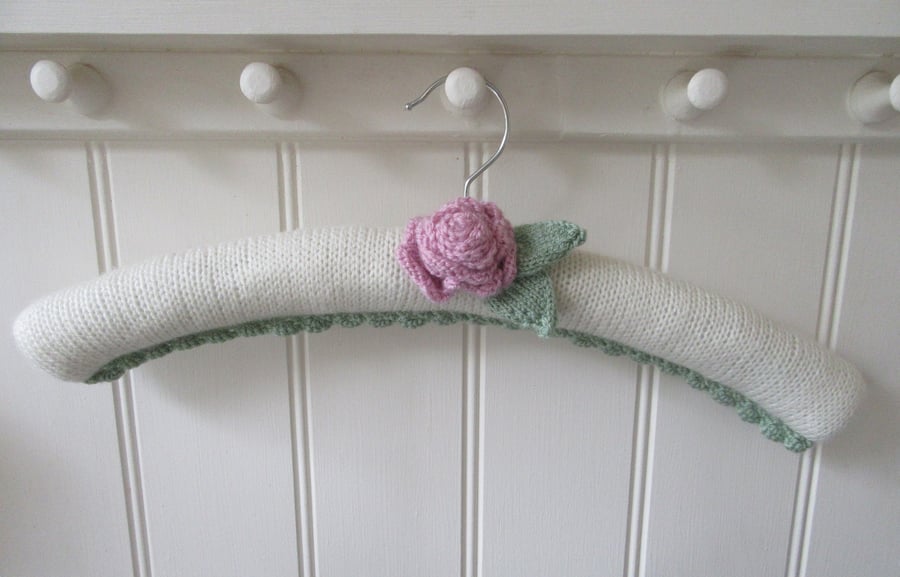 Hand knitted padded coat hanger with a ranunculus flower
