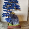Wire bonsai tree grasping hold of a large rock of amethyst 