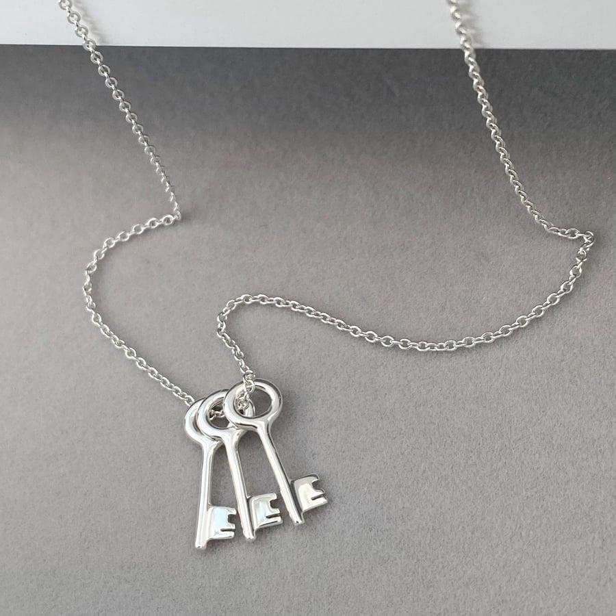 Sterling silver small and dainty key charm pendants on a trace chain.