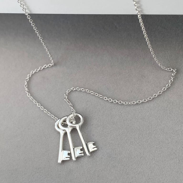 Sterling silver small and dainty key charm pendants on a trace chain.