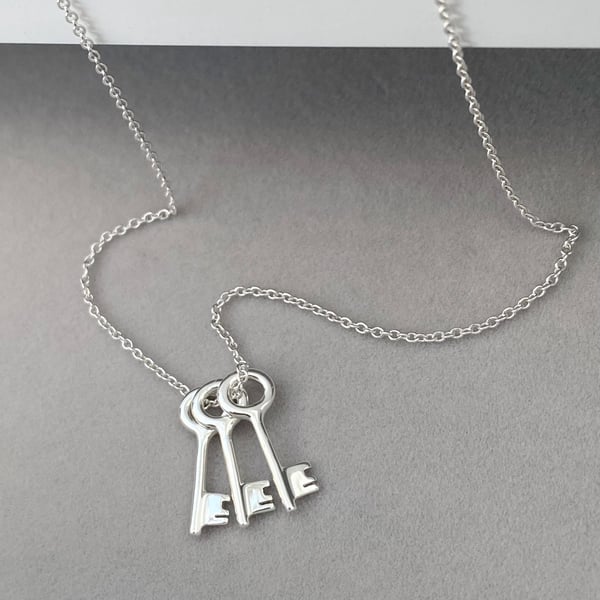 Sterling silver small and dainty key charm pendants on a trace chain.