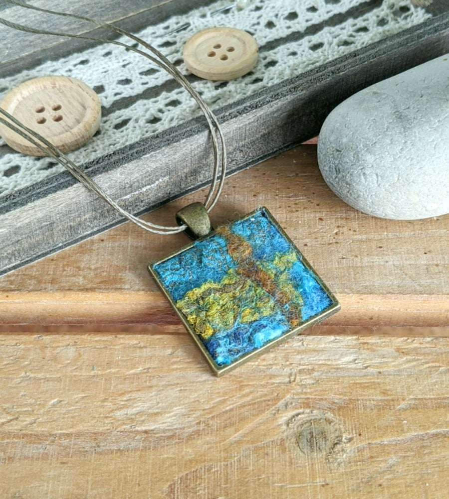 Felted square pendant - blue grey, hint of coral in a bronze bezel