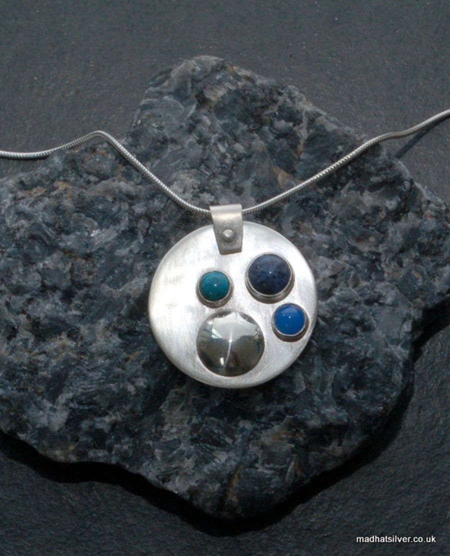 Circular silver pendant with turquoise, blue onyz and lapis lazuli