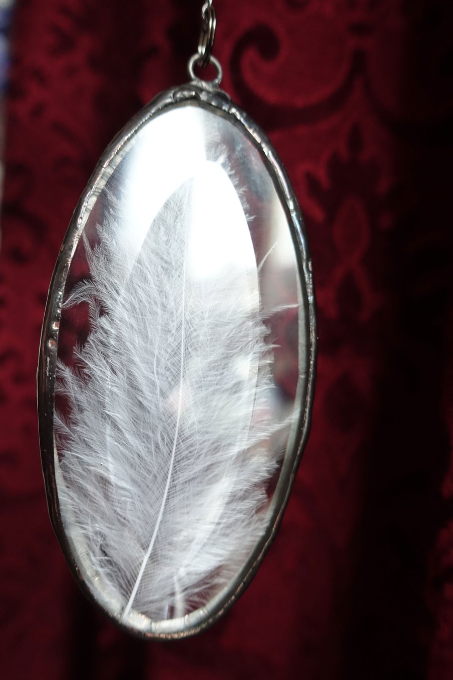 Oval Bevelled Glass Jewel with white feather embedded in the centre