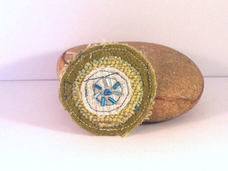 Fabric brooch, circular shape, with machine embroidery in greens