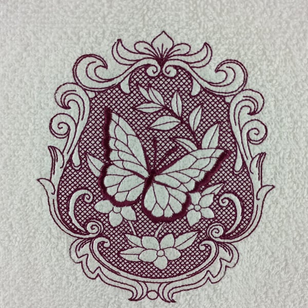 Butterfly embossed in a oval frame on a hand towel in embroidery burgundy thread