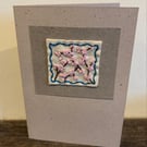 Handmade card featuring embroidered pink cherry blossoms, bordered in blue