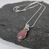 Silver and pink freeform sapphire pendant on chain.