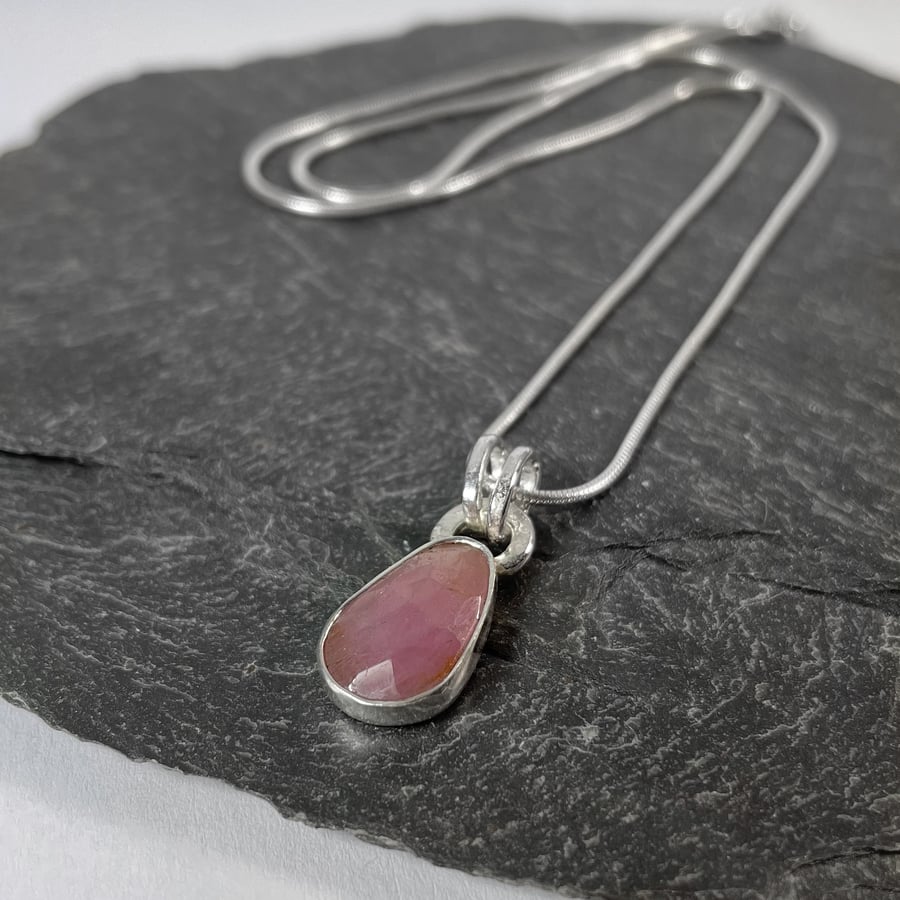 Silver and pink freeform sapphire pendant on chain.