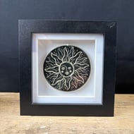 Ceramic tile with 'sun face' design presented in black shadow box frame