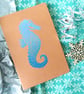 Hand printed lino seahorse motif A5 notebook in blue ink on a brown kraft cover