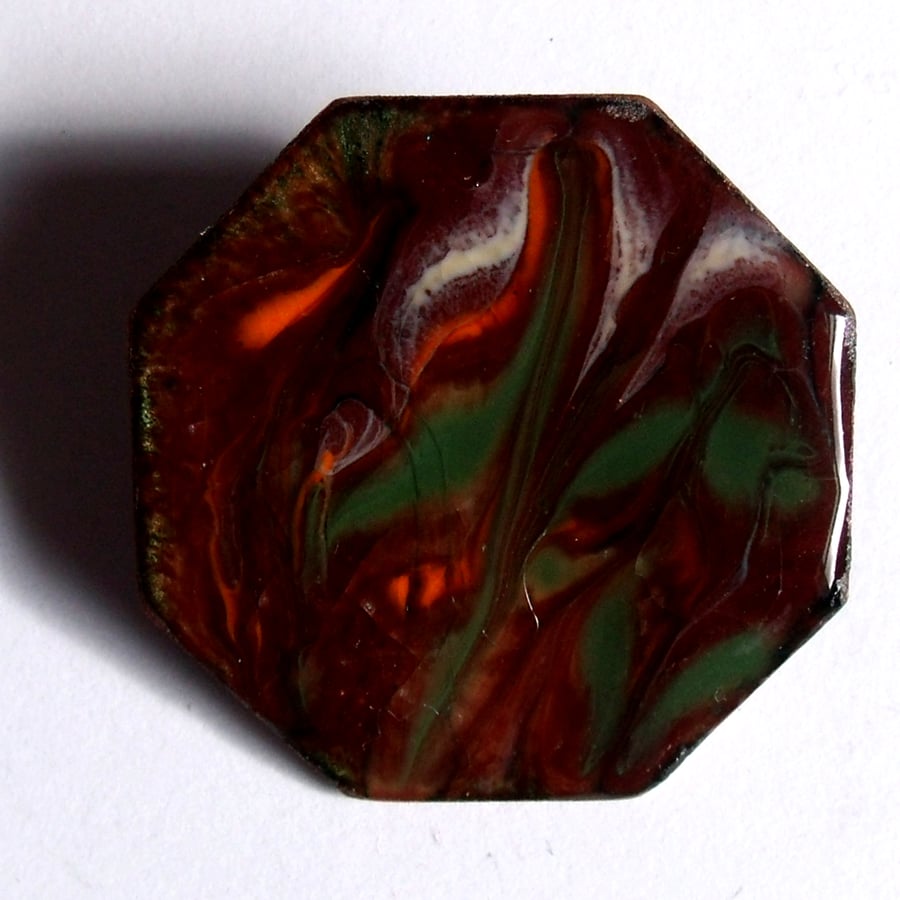 orange, green and white scrolled over red-brown on clear - brooch