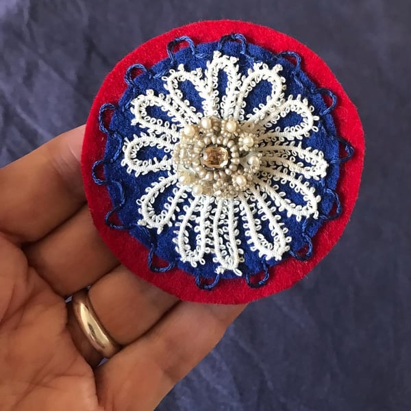 Hand embroidered corsage in red and navy felt, lace and vintage pearl centre.