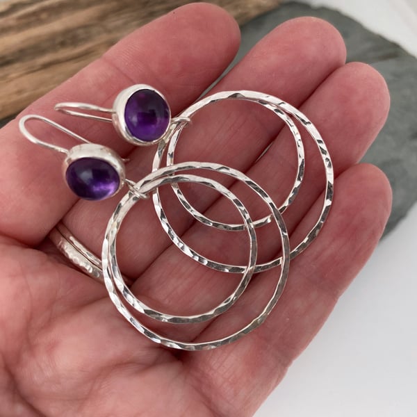 Large silver hoop earrings topped with vibrant purple Amethyst gemstones. 