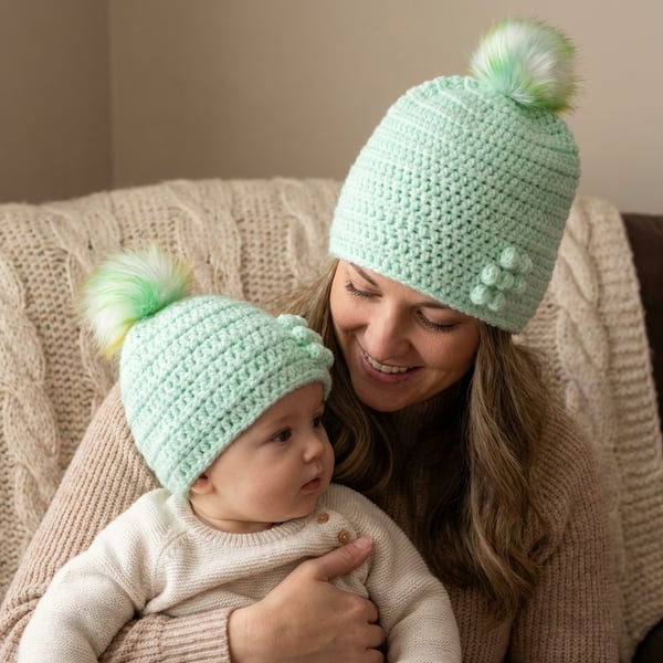 Matching ladies and baby green crocheted hats with detachable faux fur pompoms 