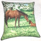 Mare and foal in a field under pretty flowering trees cushion