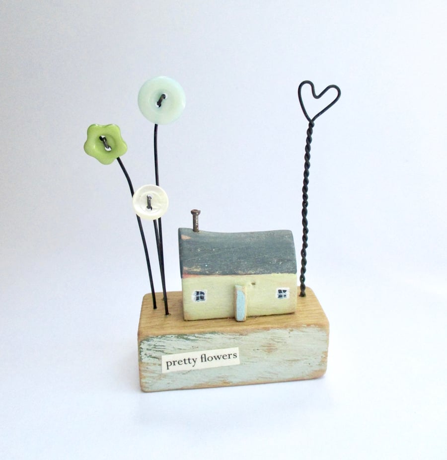Little wooden painted house with button flowers and wire heart
