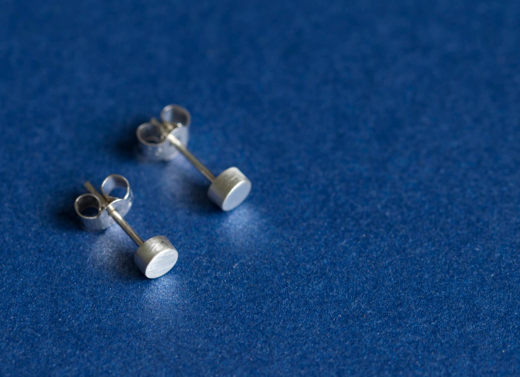 Silver cylindrical ear studs with a brush matte texture